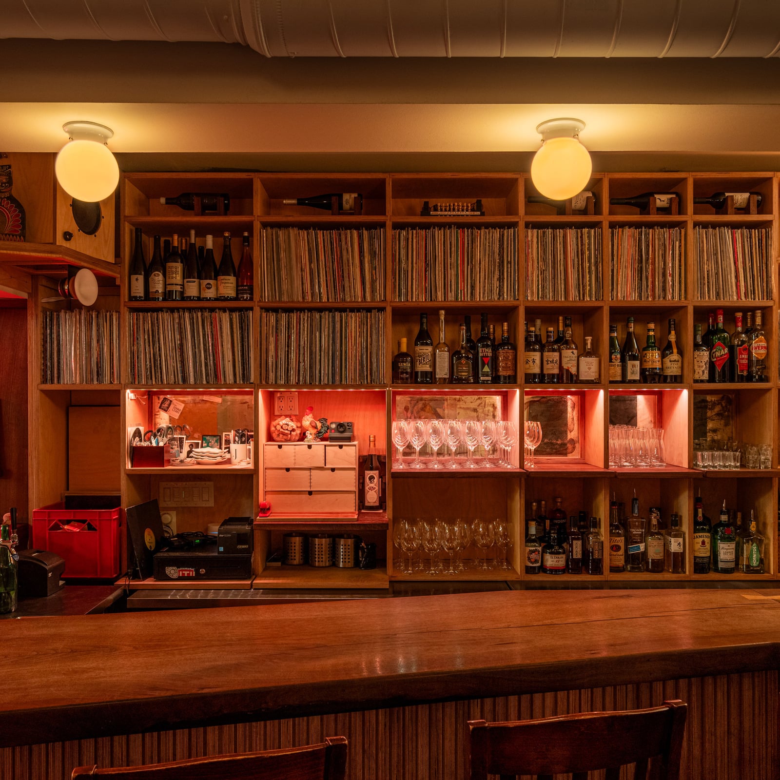 The Little Jerry’s warmly lit wooden bar, with shelves of vinyl records and bottles.